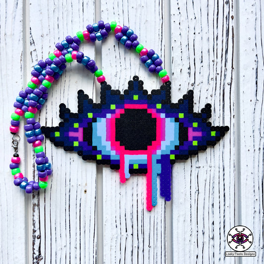 Evil Eye Dripping perler necklace by leaky pixels. Eye with dilated pupil bleeding pink, blue and purple liquid.