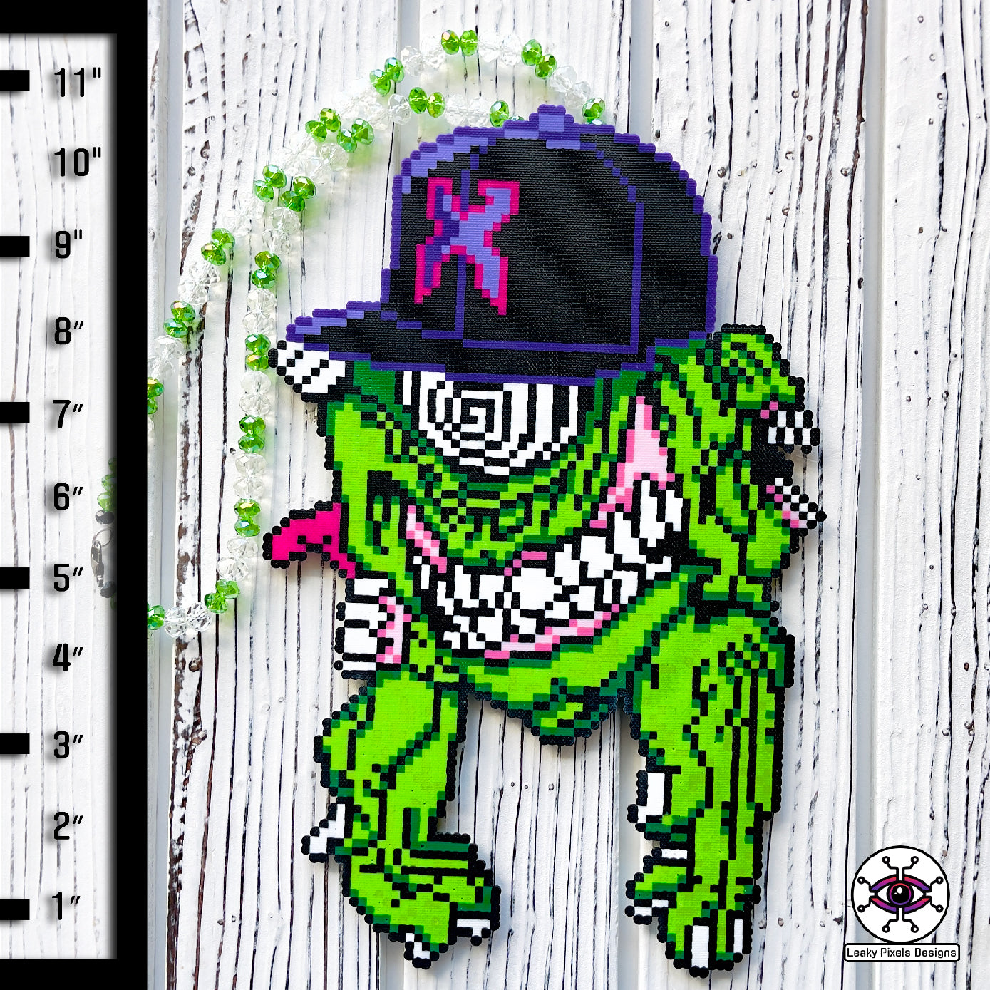 Excision Subtronics Cyclops Perler Necklace Green. One eyed green cyclops monster with hypnotizing rezz spiral eye. Two mouths are on each side of its head one with its tongue sticking out. big grin on its face bearing teeth and long hands below him.