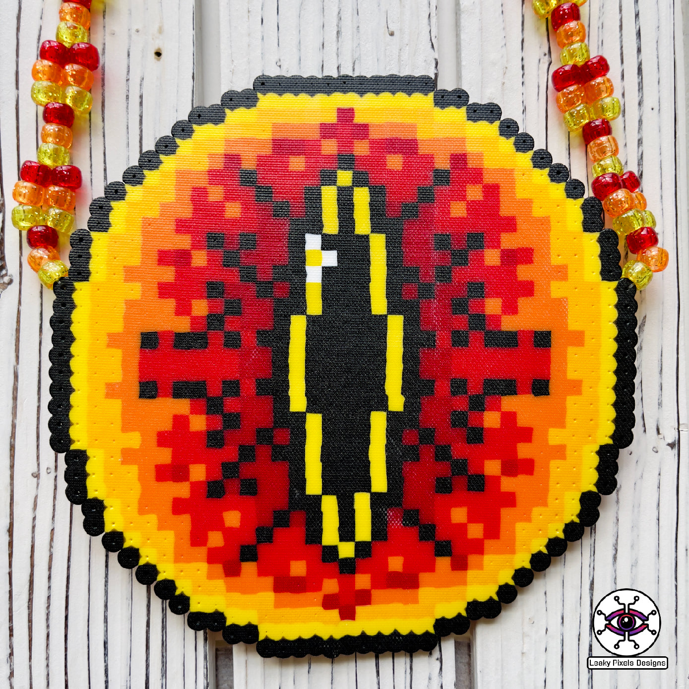 Eye of sauron perler necklace. Large fiery eye with darkness inside it. from Lord of the rings. has red, orange and yellow pony beads as a necklace.