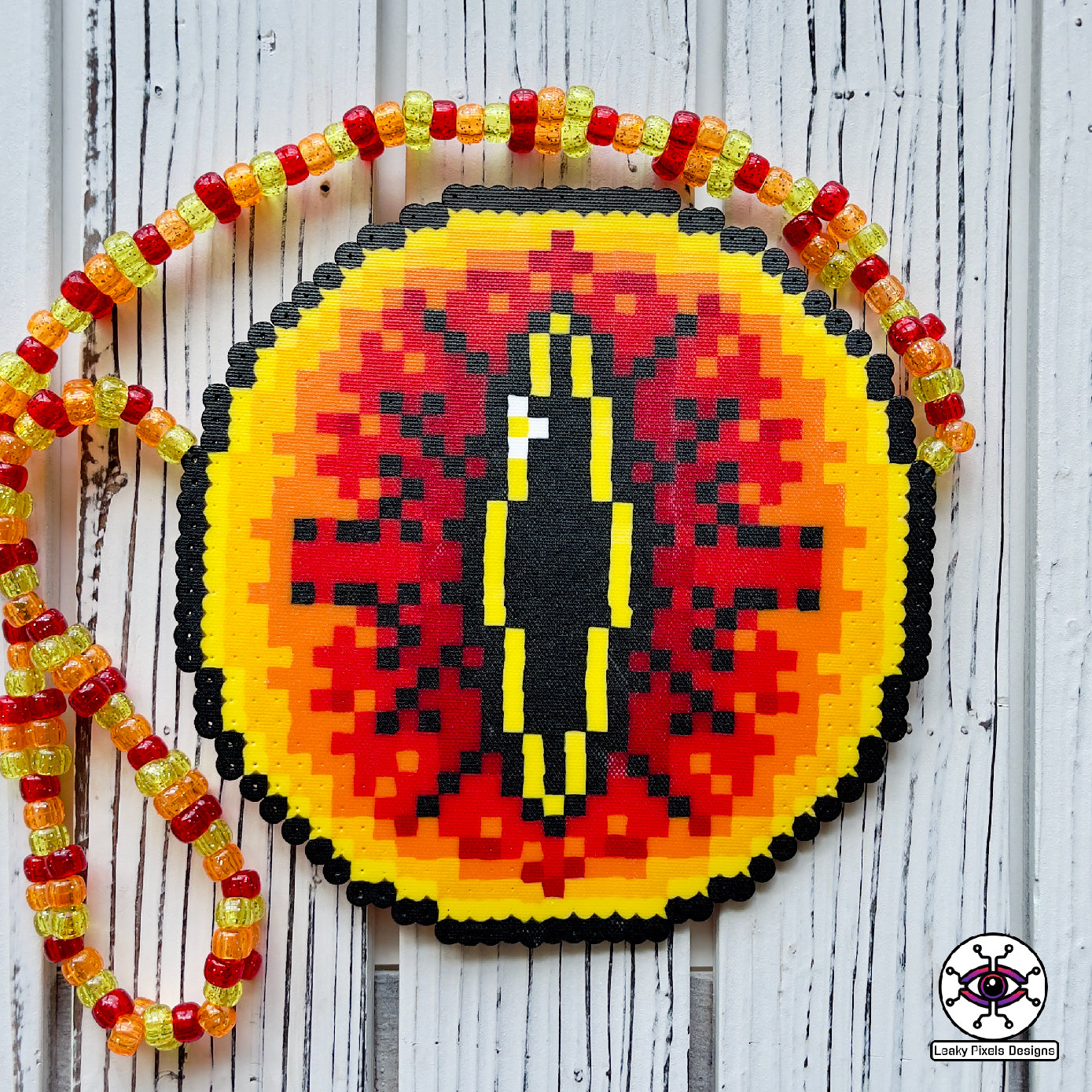 Eye of sauron perler necklace. Large fiery eye with darkness inside it. from Lord of the rings. has red, orange and yellow pony beads as a necklace.