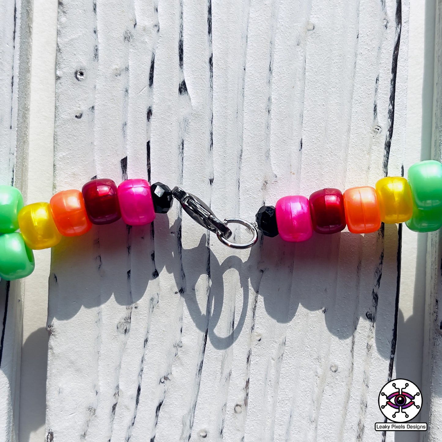 rainbow perler necklace by leaky pixels. red, orange, yellow, green, blue, purple and pink. black storm cloud and pink cloud.