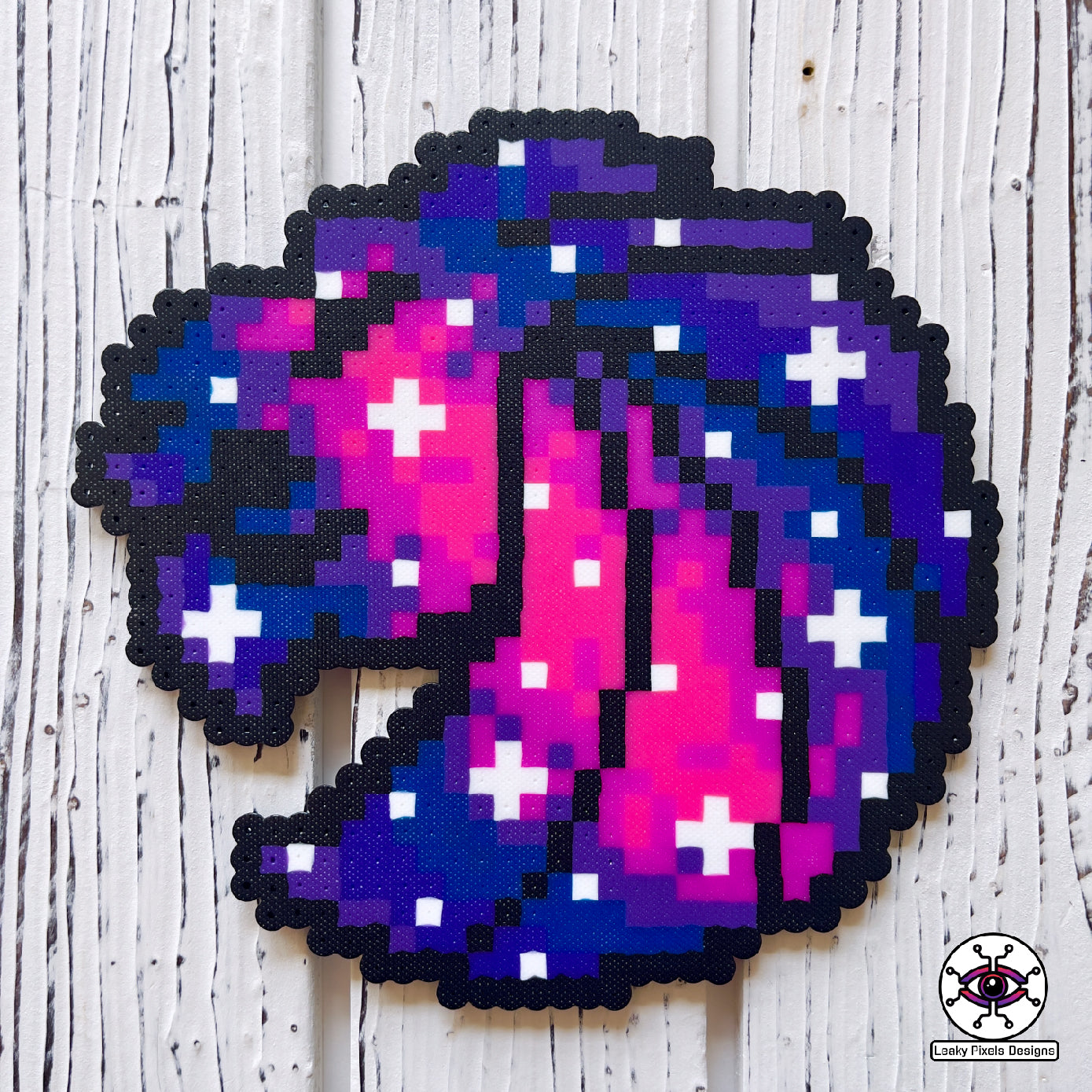 Seven Lions galaxy perler necklace. seven lions logo made of purple, pink, teal, blue and white starts. image of a galaxy. necklace is made of purple, blue, and pink pearl pony beads.
