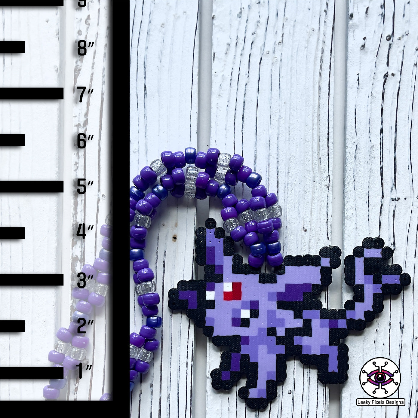 Espion perler necklace. Perler of the pokemon Espion that is cat like with fur colors of lavender and purple. Has a red gem stone on her forehead. Pony beads are purple for the necklace.