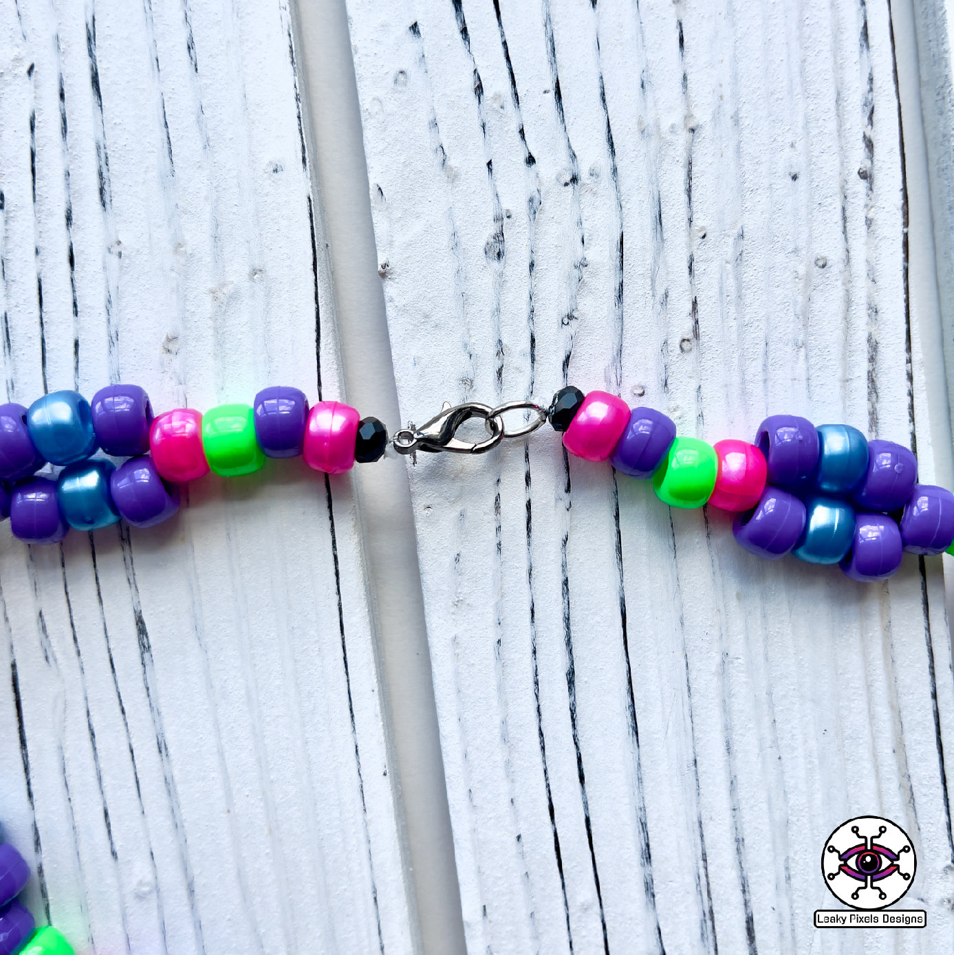 Evil Eye Dripping perler necklace by leaky pixels. Eye with dilated pupil bleeding pink, blue and purple liquid.