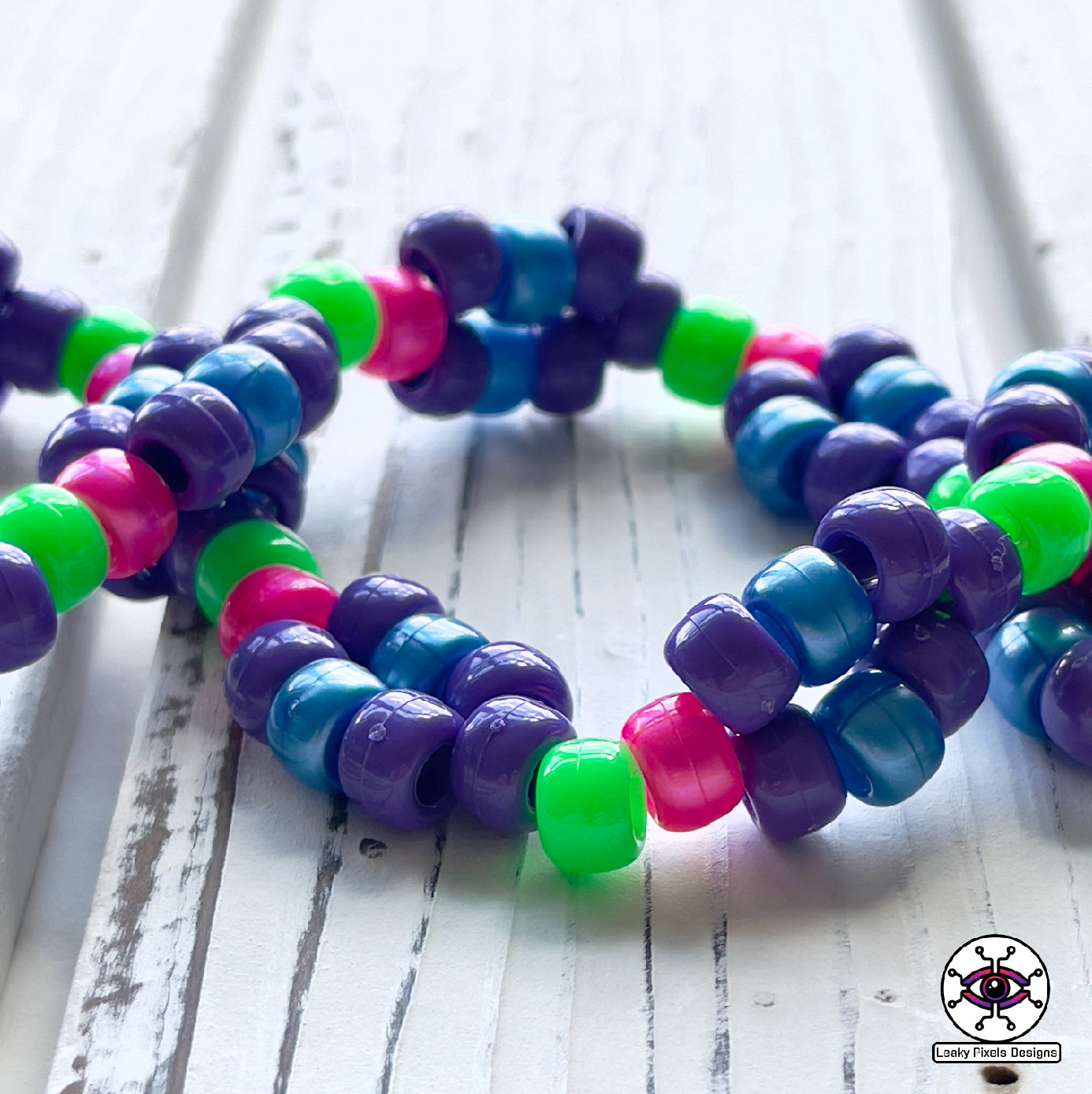 Evil Eye Dripping perler necklace by leaky pixels. Eye with dilated pupil bleeding pink, blue and purple liquid.