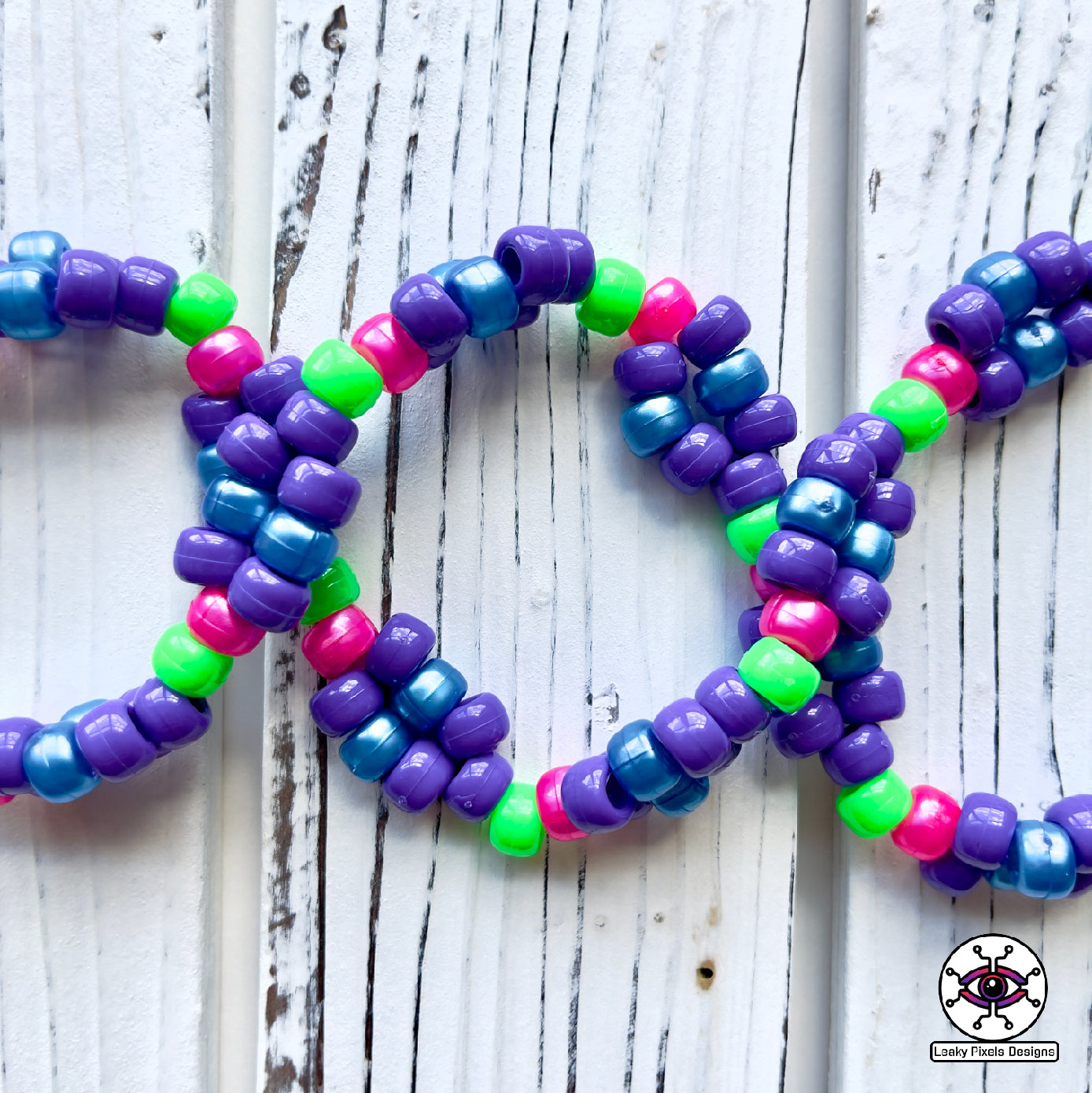 Evil Eye Dripping perler necklace by leaky pixels. Eye with dilated pupil bleeding pink, blue and purple liquid.