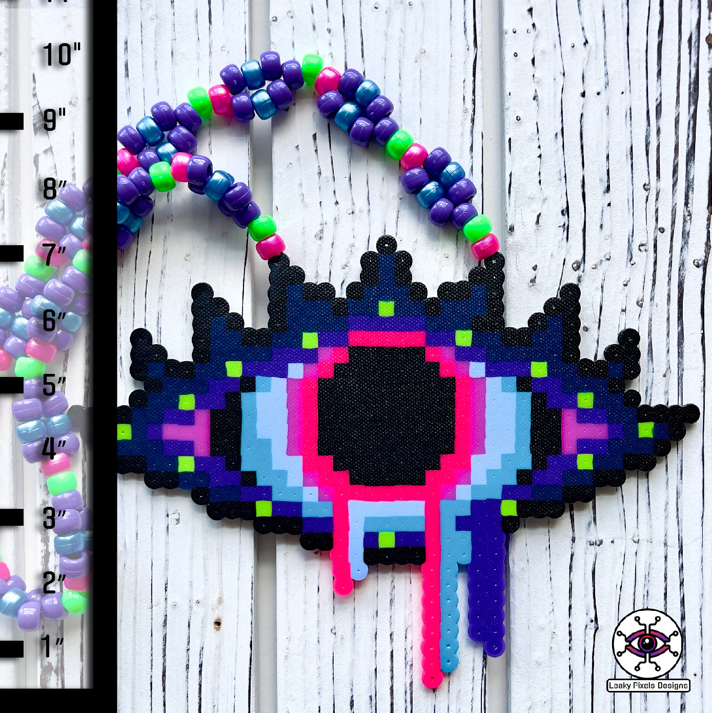 Evil Eye Dripping perler necklace by leaky pixels. Eye with dilated pupil bleeding pink, blue and purple liquid.