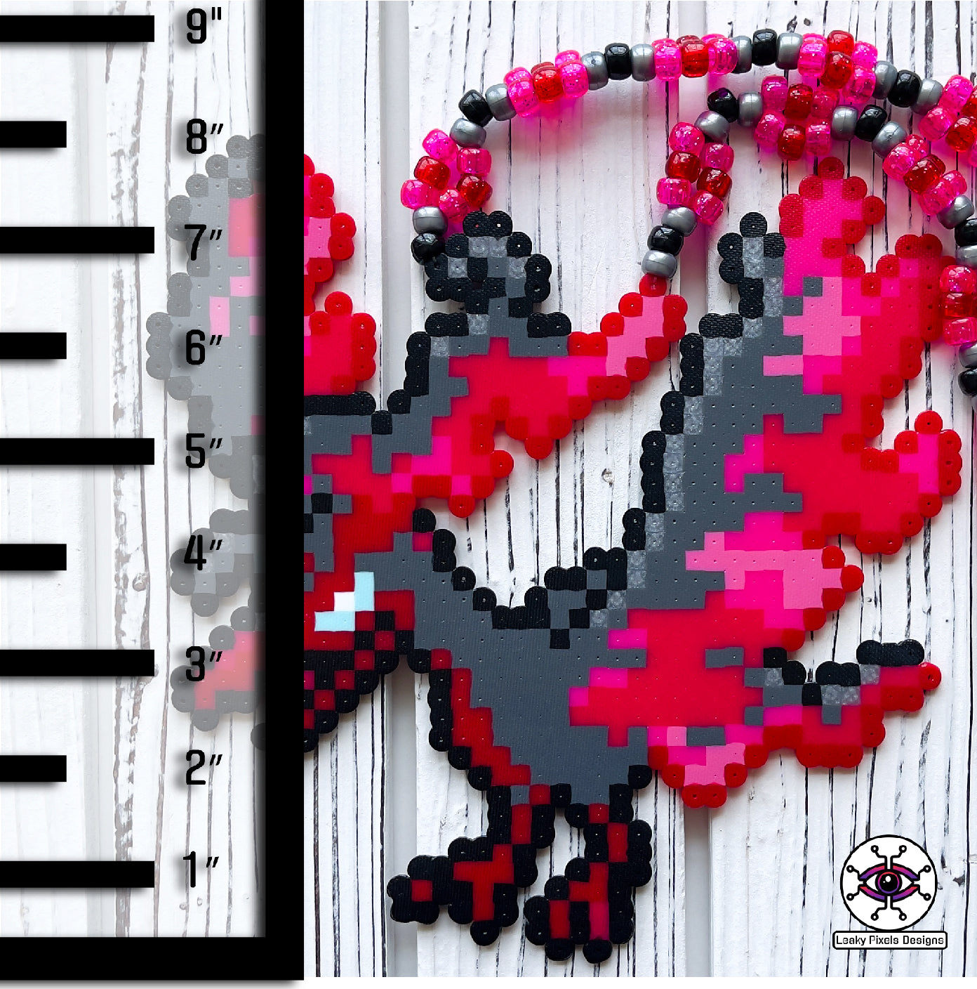 galarian moltres pokemon perler necklace made by leaky pixles. megenta, pink and red legendary bird with fire wings. dark grey body.pink and red glitter pony beads make up the necklace.