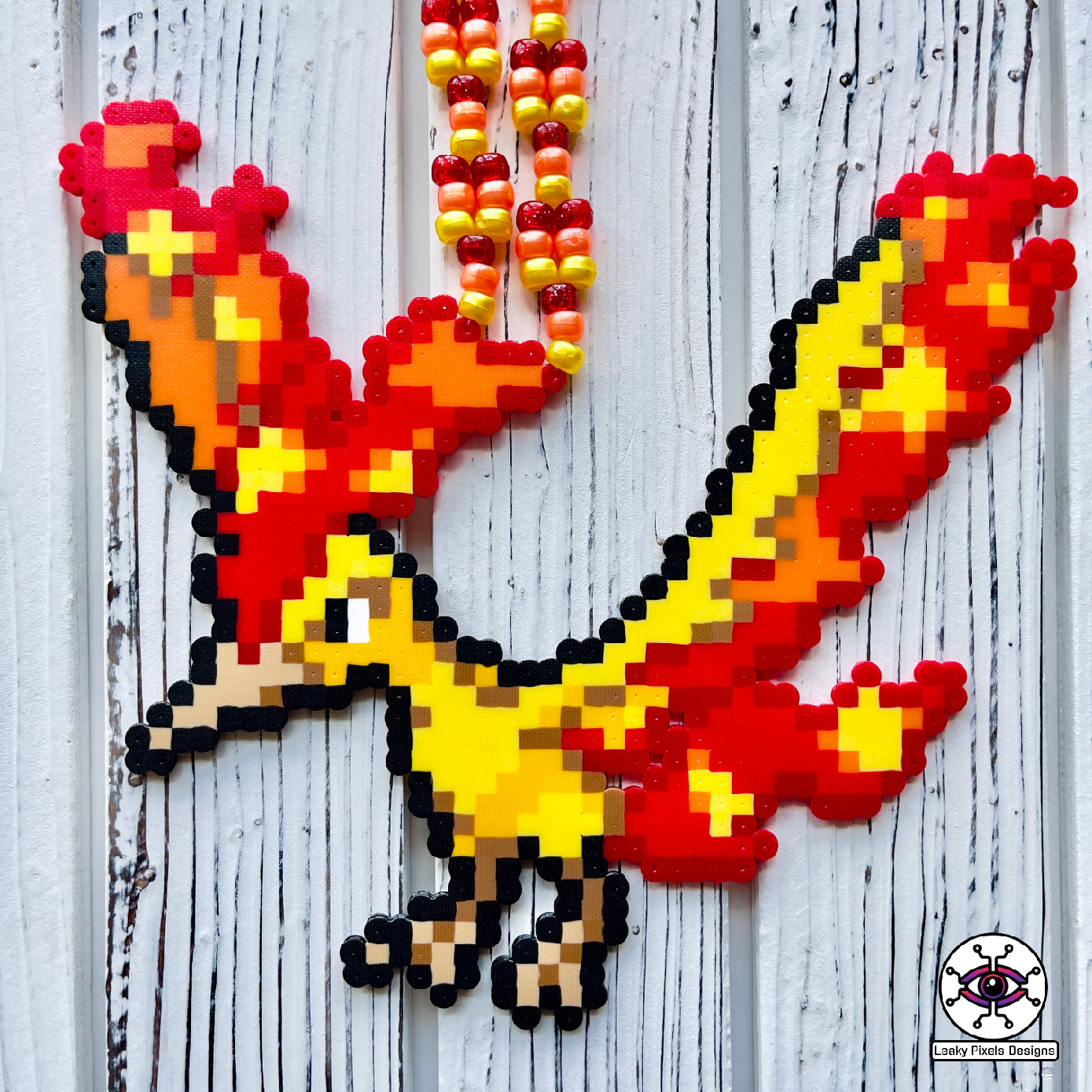 Moltres pokemon perler necklace made by leaky pixels. fire type legendary bird with fire blazing from its body. perlernecklace is made from orange, red and yellow pony beads.