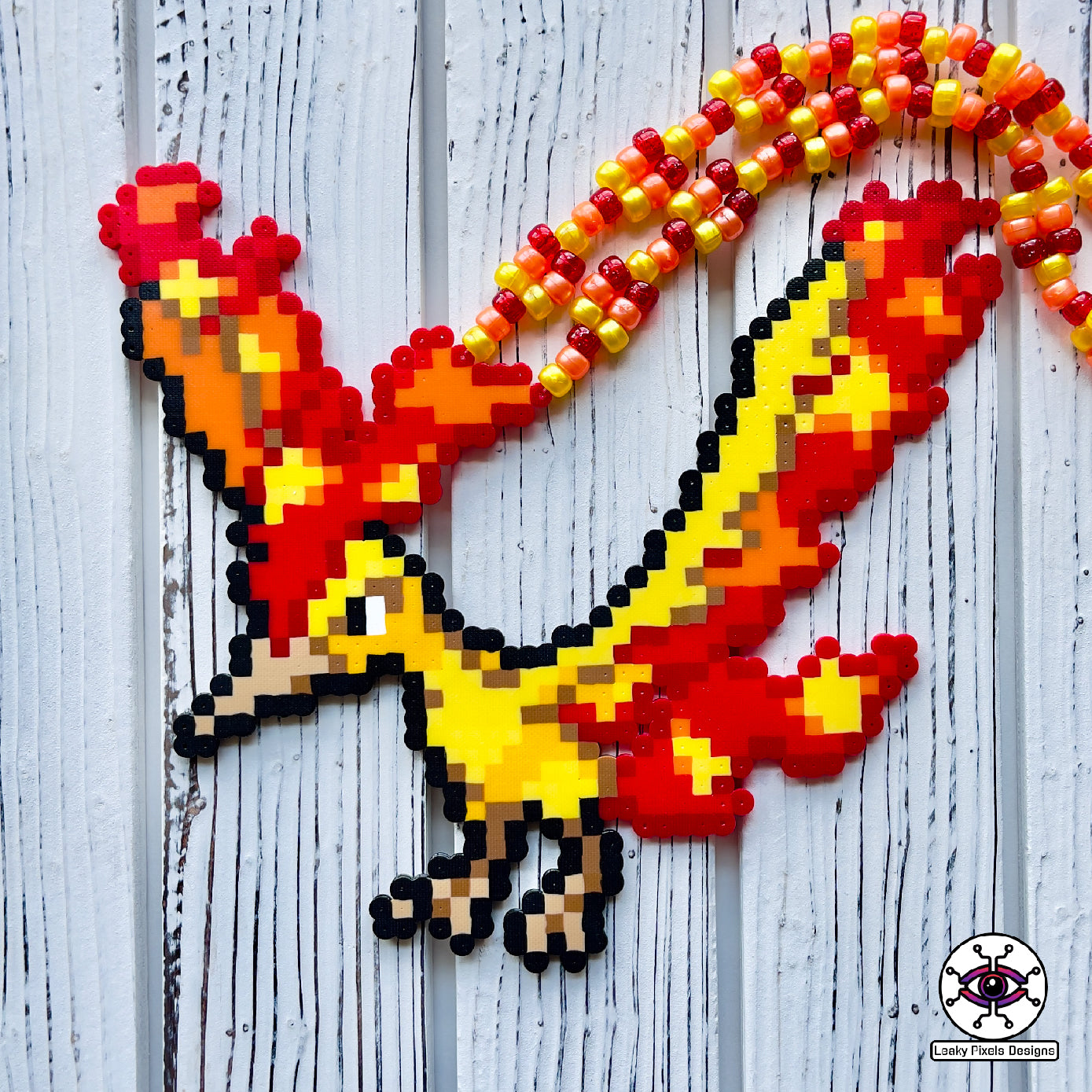 Moltres pokemon perler necklace made by leaky pixels. fire type legendary bird with fire blazing from its body. perlernecklace is made from orange, red and yellow pony beads.