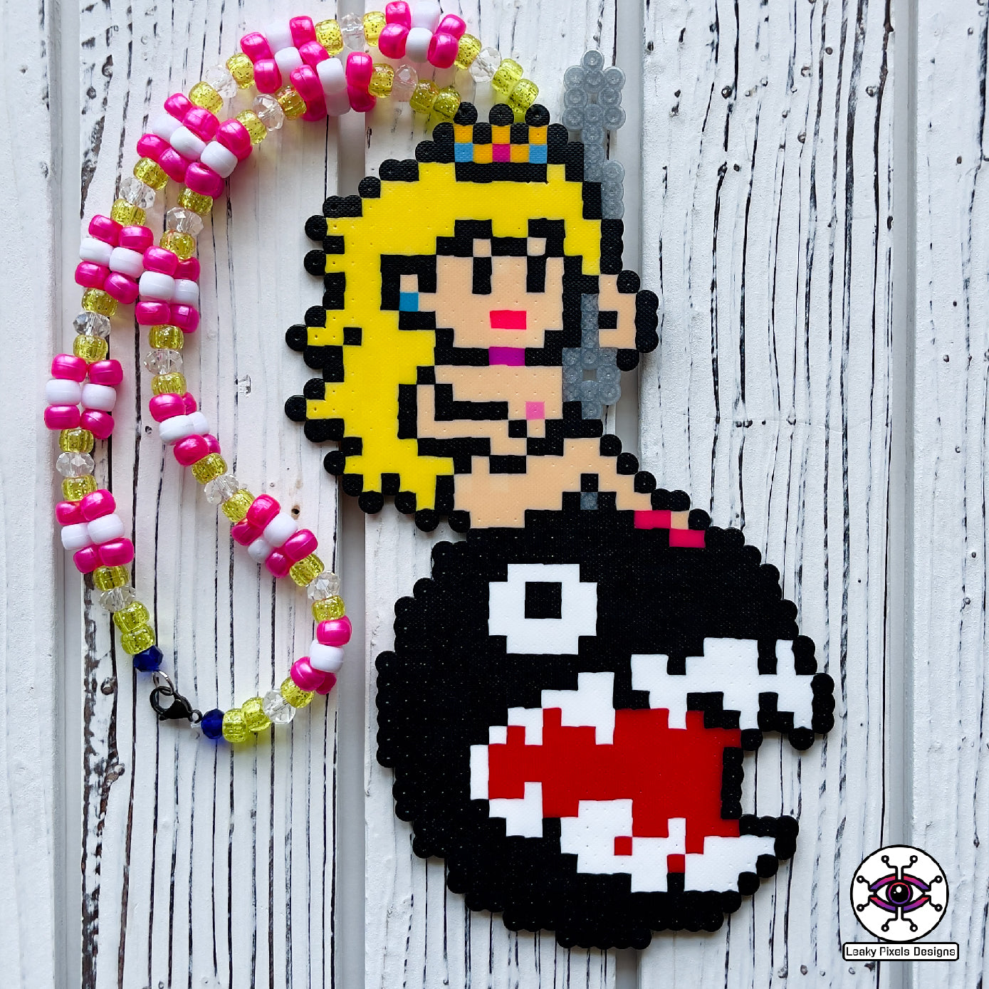 Princess peach perler necklace made by leaky pixels. princess peach nude swinging on a wrecking ball chain chomp from super mario bros.