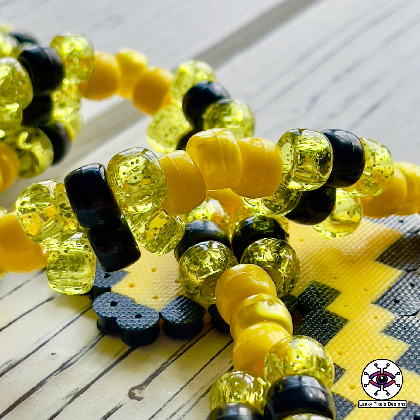 pokemon pikachu yellow perler necklace. Necklace is made of yellow glitter yellow pearl, yellow and black pony beads with a clasp. Pikachu is running with a smile.