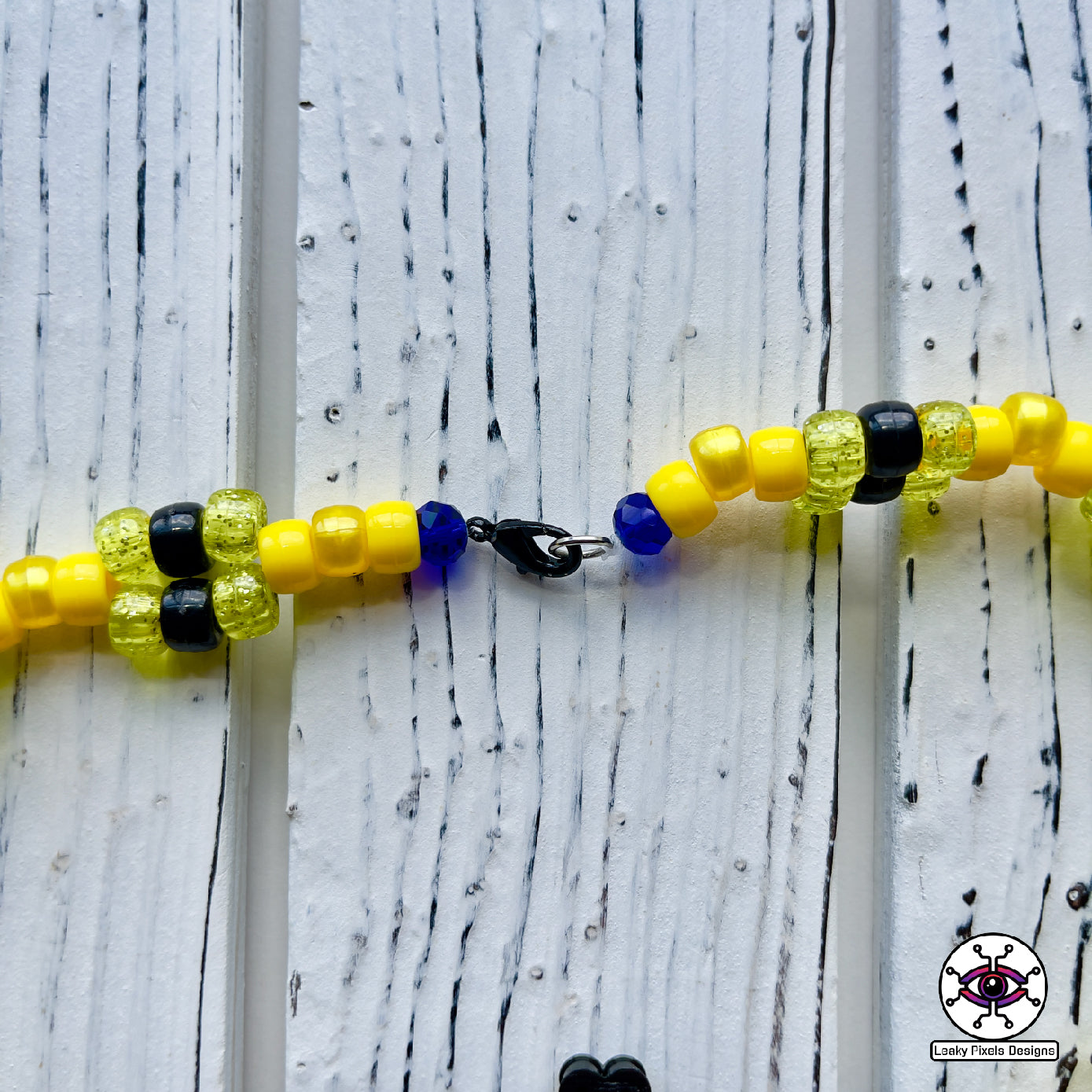 pokemon pikachu yellow perler necklace. Necklace is made of yellow glitter yellow pearl, yellow and black pony beads with a clasp. Pikachu is running with a smile.