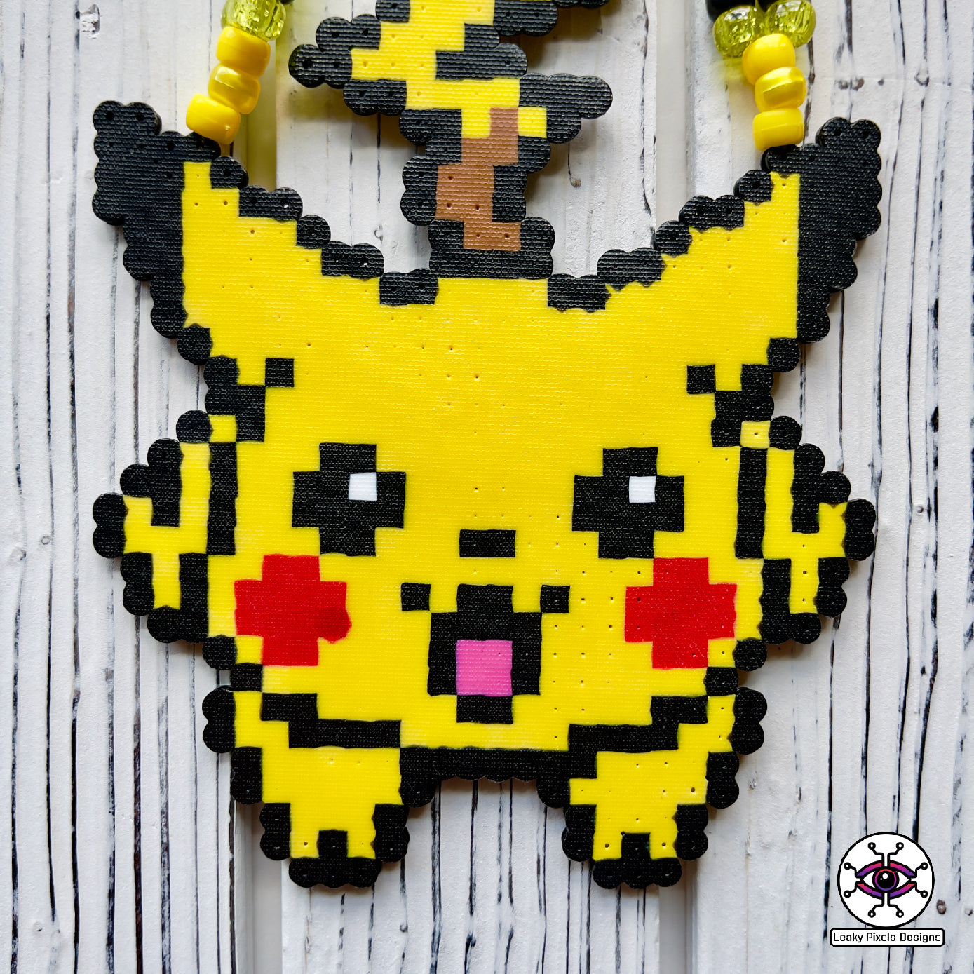 pokemon pikachu yellow perler necklace. Necklace is made of yellow glitter yellow pearl, yellow and black pony beads with a clasp. Pikachu is running with a smile.