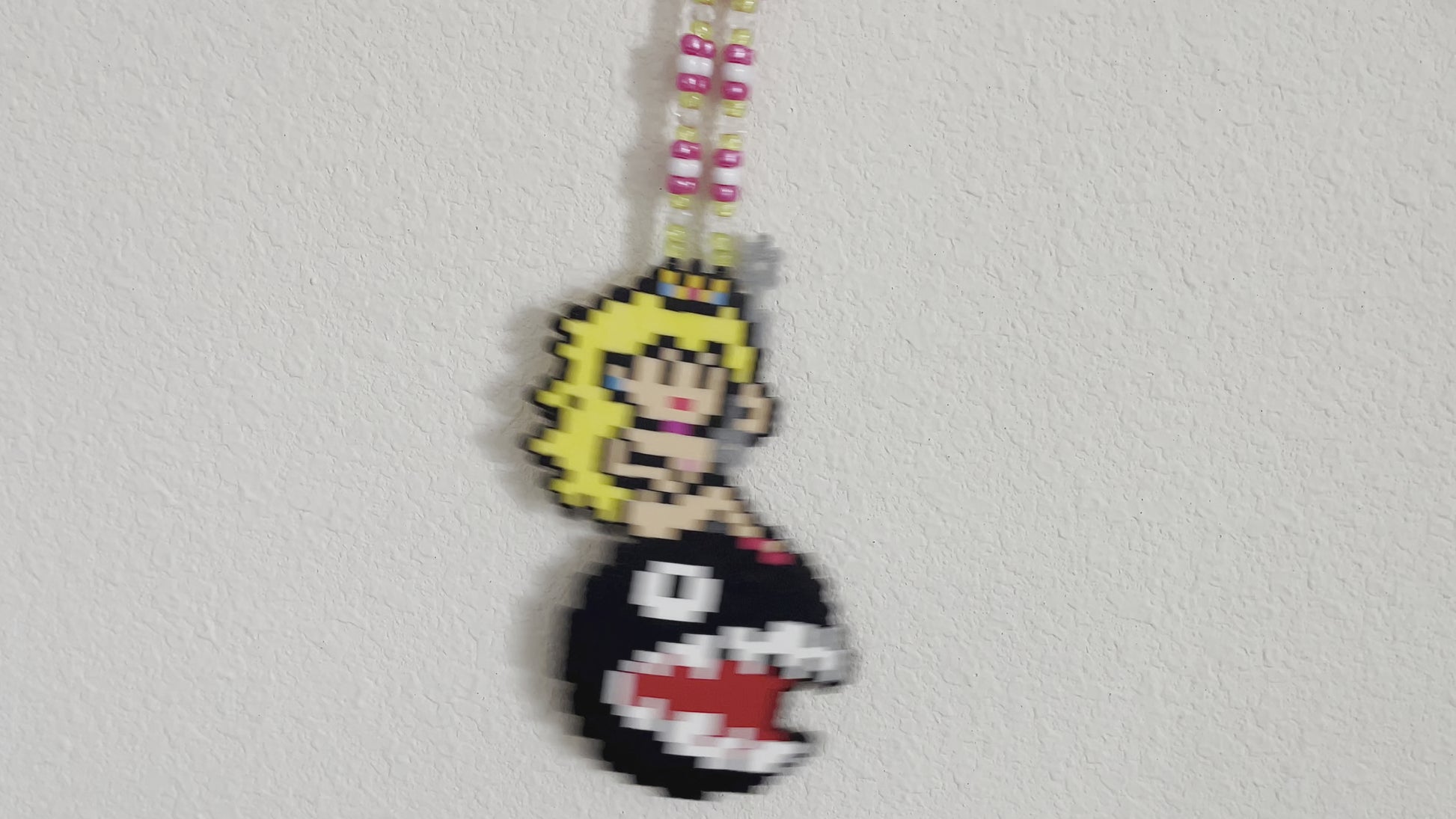 Princess peach perler necklace made by leaky pixels. princess peach nude swinging on a wrecking ball chain chomp from super mario bros.