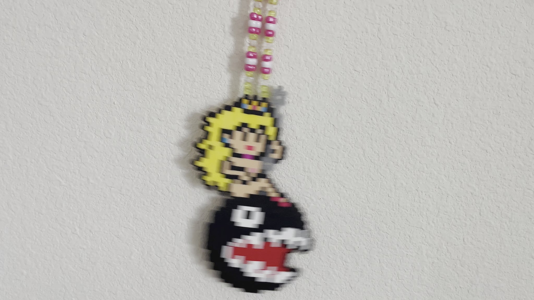 Princess peach perler necklace made by leaky pixels. princess peach nude swinging on a wrecking ball chain chomp from super mario bros.